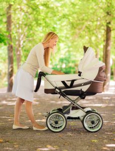 family, child and parenthood concept - happy mother with stroller in park