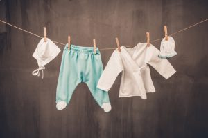 White baby goods hanging on the clothesline on grey background